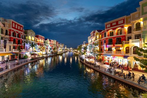 Free Illuminated canal cityscape with vibrant European-style buildings reflecting at night. Stock Photo