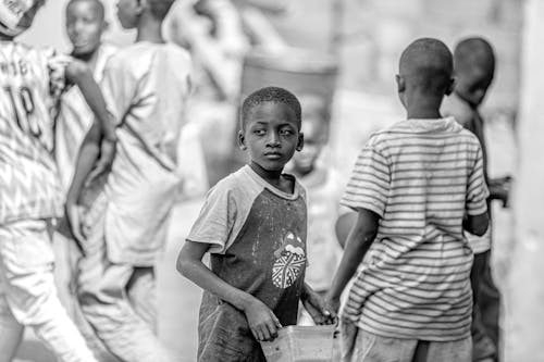 Grayscale Photo of a Boy Holding a Plastic Container