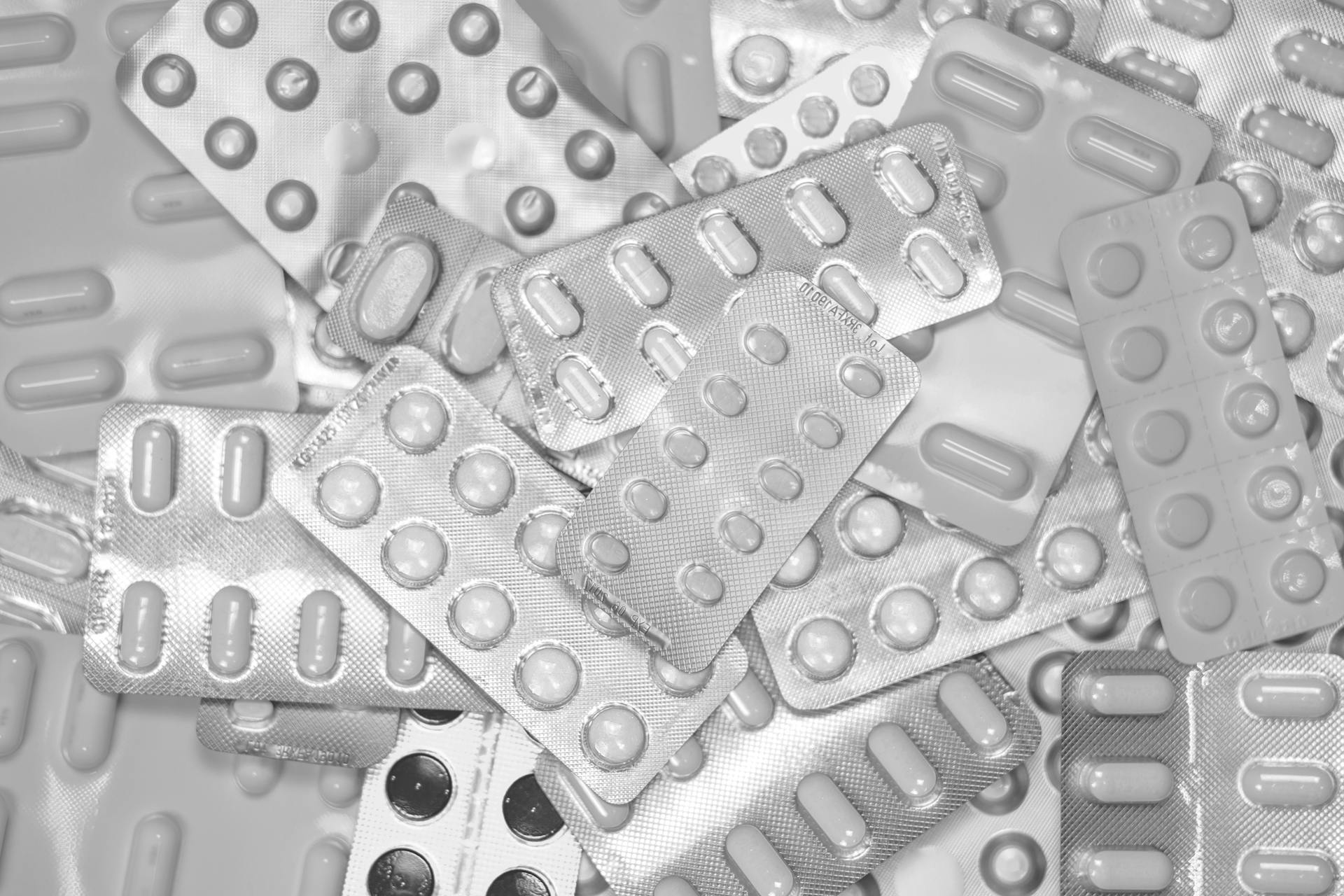 Monochrome close-up of assorted blister packs with pills, highlighting pharmaceutical packaging.