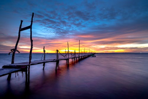 Wooden Dock on Ocean During Sunset