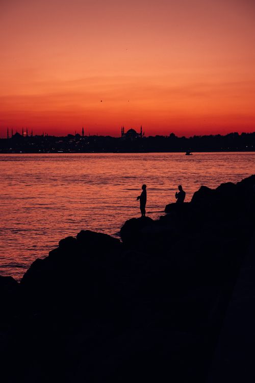 Free Peaceful silhouette scene at sunset over a city skyline across the ocean, capturing nature's beauty. Stock Photo