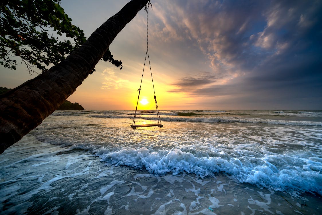 Free A Swing Over Sea Waves During Sunset Stock Photo
