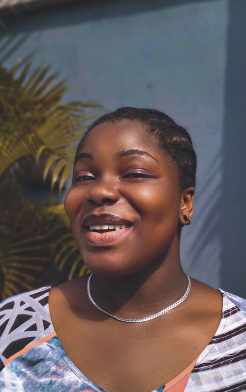Free Portrait of a smiling woman with braided hair, captured outdoors in bright sunlight. Stock Photo