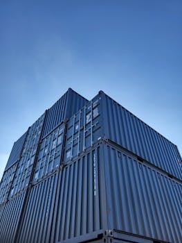 Low angle view of stacked cargo containers with clear blue sky background.