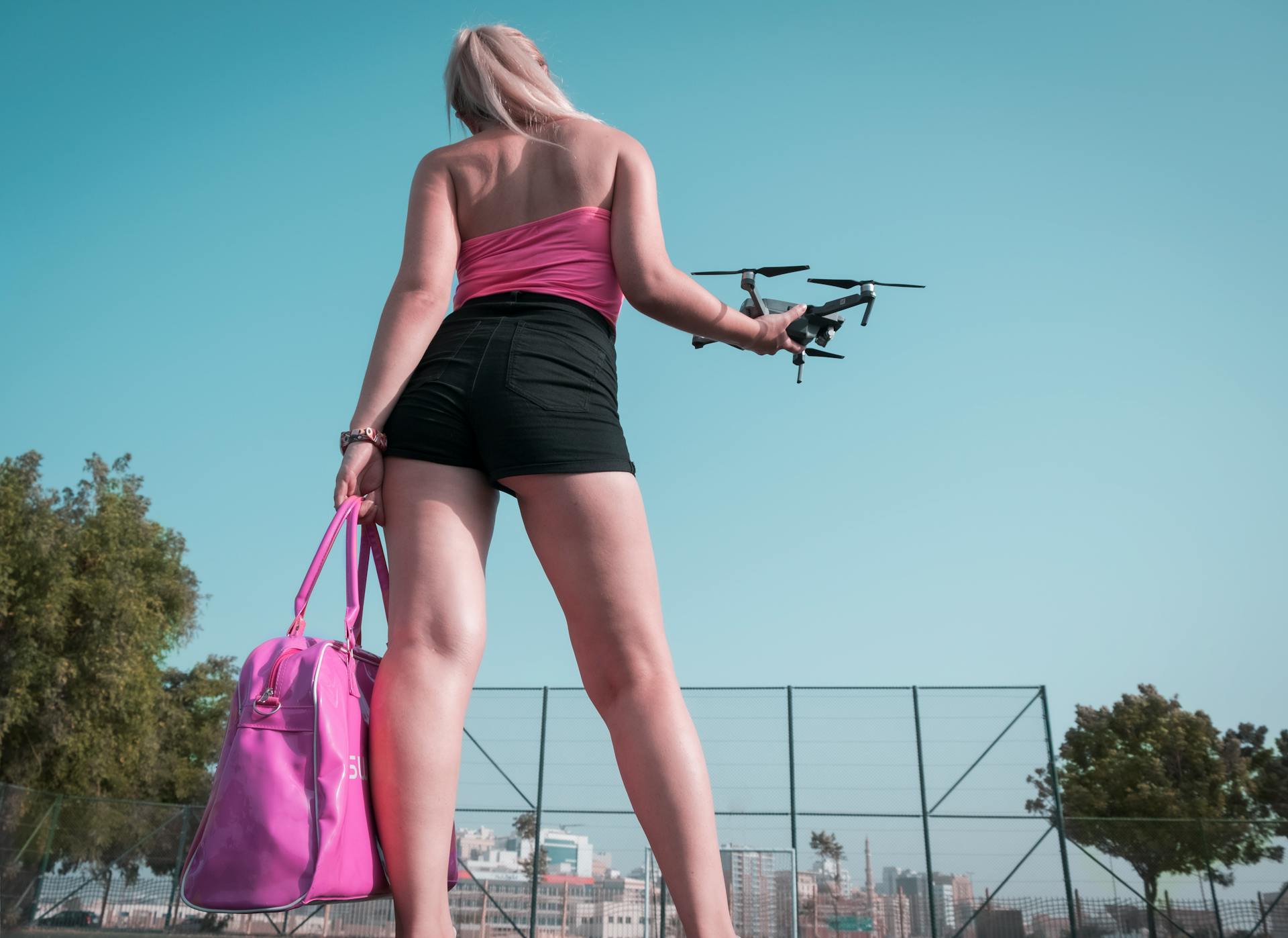 A stylish woman holding a drone in an urban outdoor setting in Dubai.