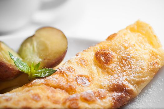A close-up of a sweet crepe dusted with powdered sugar and garnished with fresh fruit.