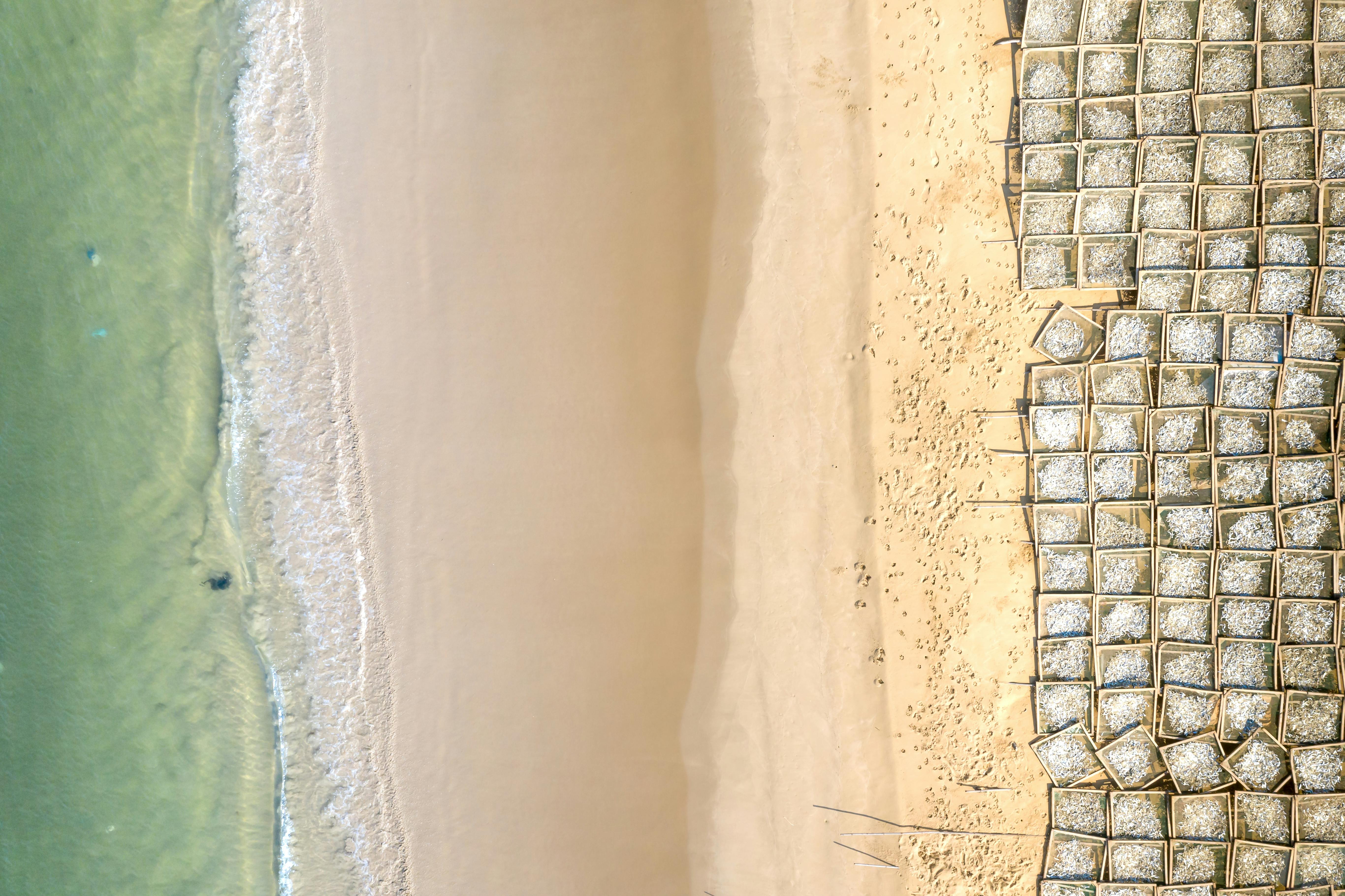 Free Aerial shot of a tranquil beach with unique sand patterns and ocean waves. Stock Photo