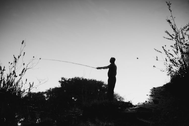 Silhouette Of Man On Bank Fishing 