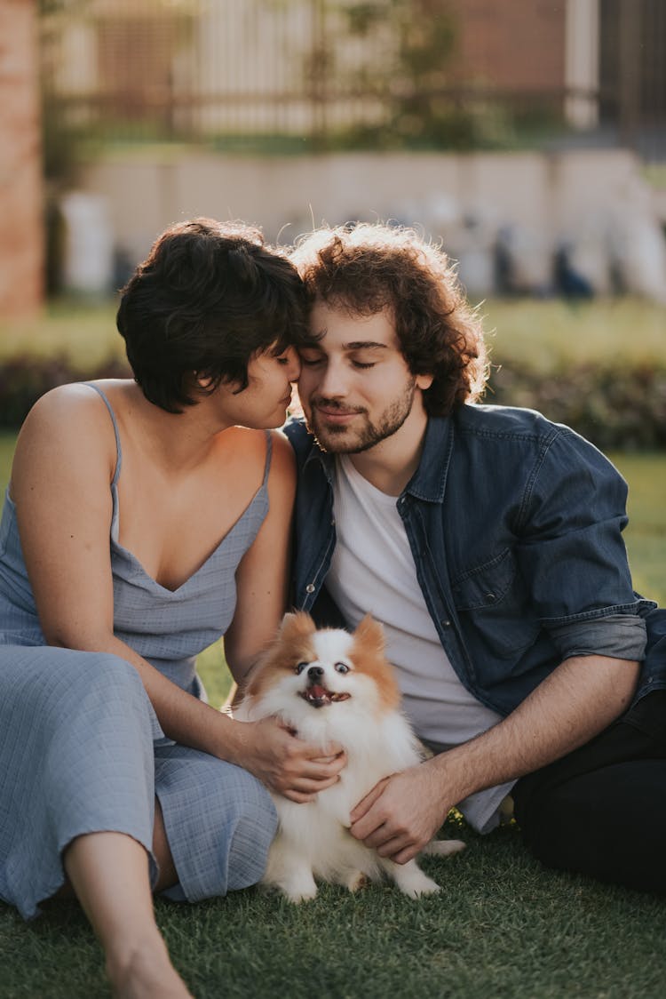 Couple With Dog Sitting On Ground Cuddling