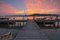 平静的湖面上映着日落，木制码头和停泊的船只营造出宁静的氛围