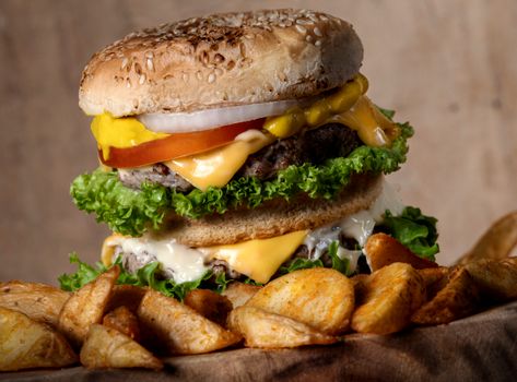 Delicious cheeseburger stacked with ingredients alongside crispy potato wedges, served in Guanajuato, Mexico.