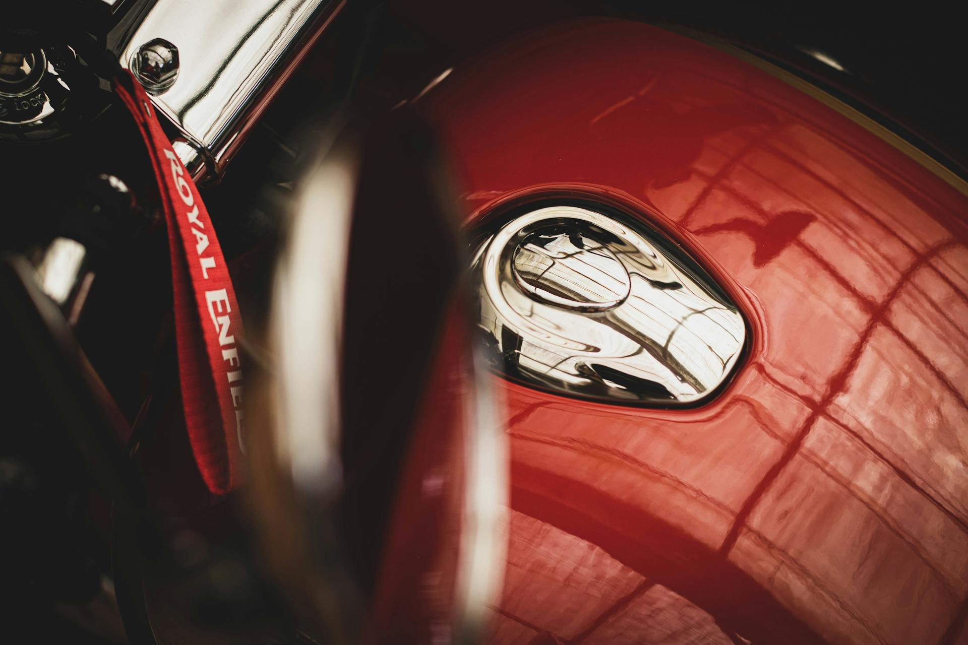 Detailed close-up of a classic red Royal Enfield motorcycle fuel tank featuring a logo.