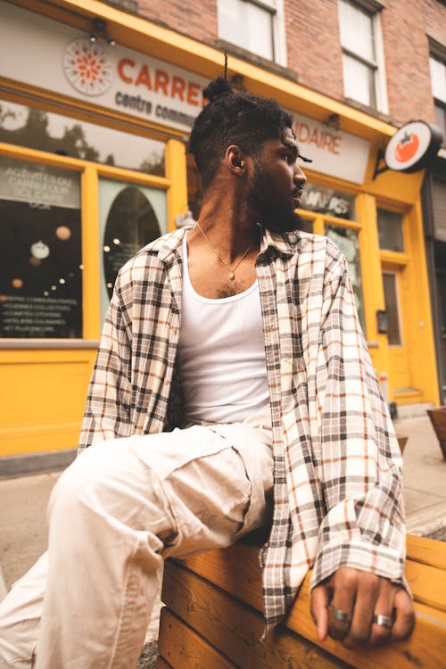 A Man in Plaid Long Sleeves Sitting on the Street while Looking Over Shoulder