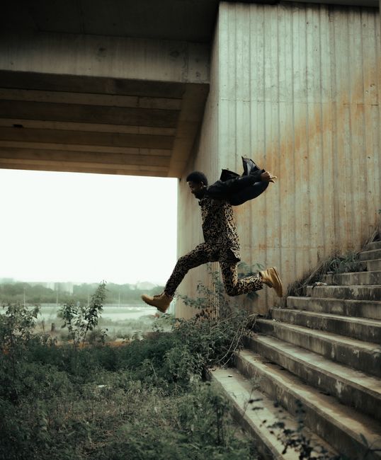 Dynamic shot of a man leaping mid-air in an urban setting, symbolizing freedom and energy.