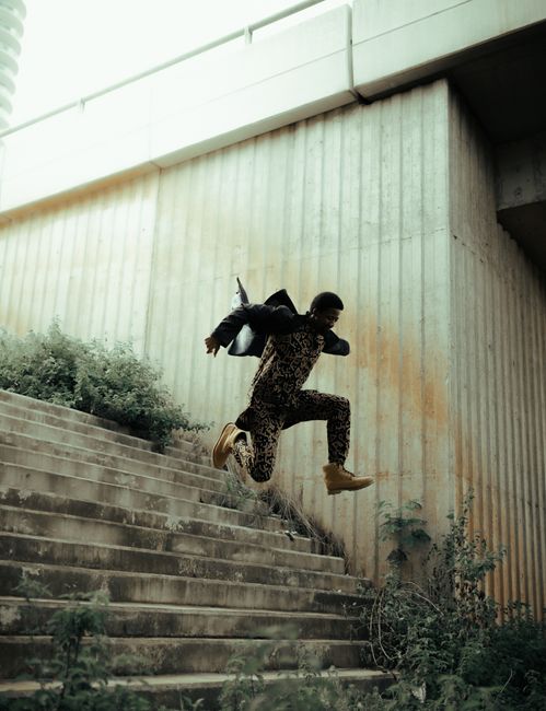 A man energetically jumps down stair steps in an urban setting in Lagos, Nigeria.
