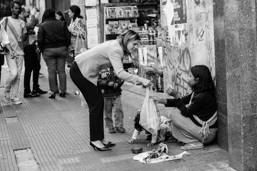 Woman Helping a Mother with a Child Begging on the Street 