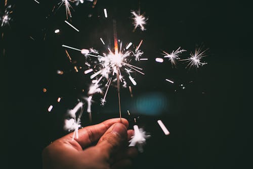 Person Holding White and Green Fireworks