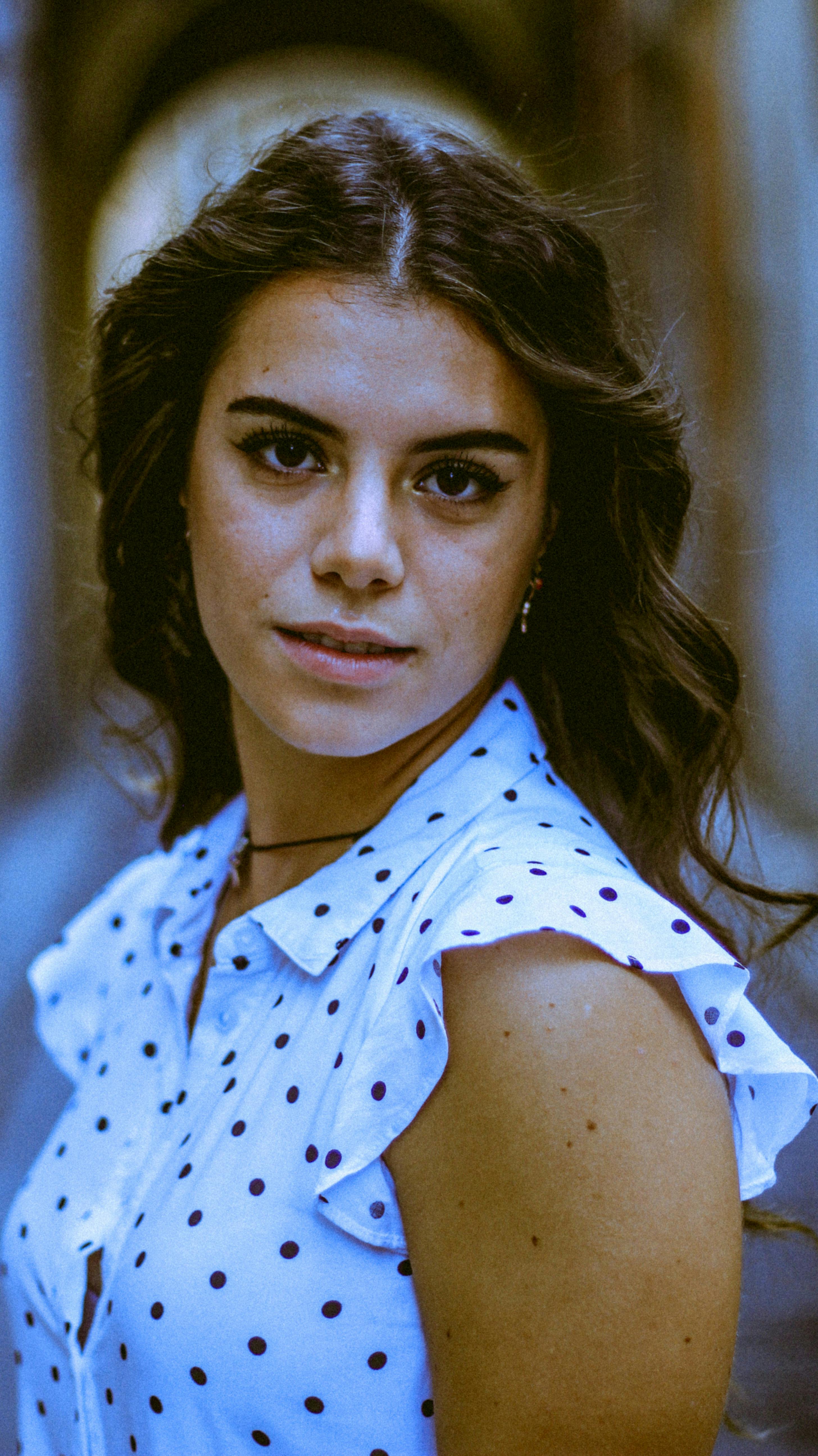 Elegant portrait of a brunette woman in a polka dot top, photographed in Ragusa, Sicily.