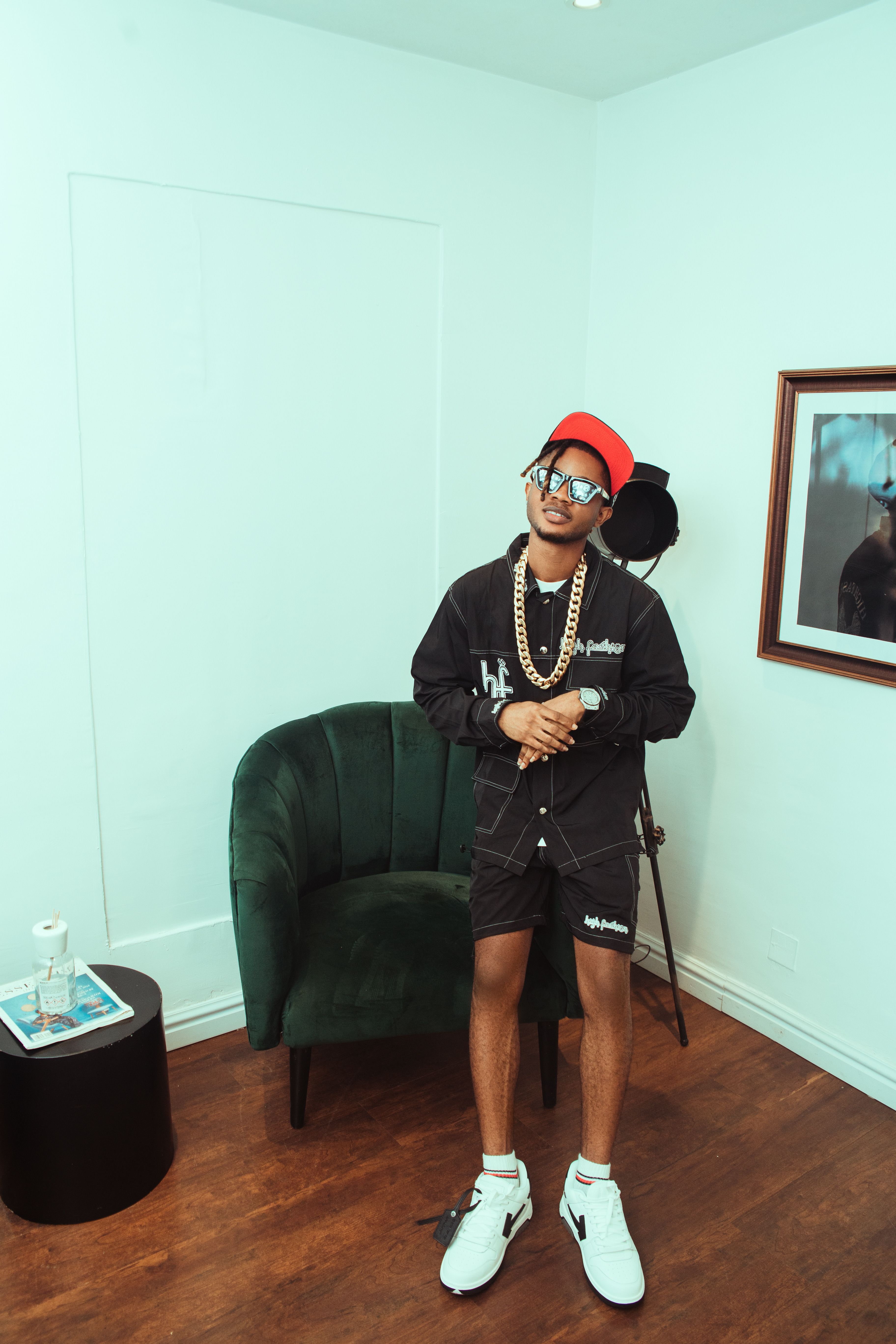 Stylish man indoors wearing a casual outfit with hat and sunglasses.