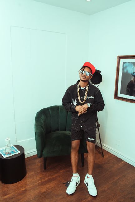 Stylish man indoors wearing a casual outfit with hat and sunglasses.