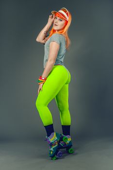A young woman in vibrant leggings and roller skates poses elegantly against a studio backdrop.