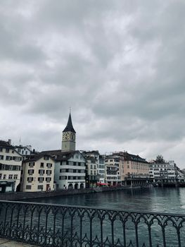 Charming cityscape of Zürich with historic buildings along the Limmat River under a cloudy sky.