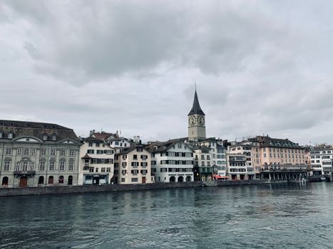 A picturesque view of Zurich's riverfront featuring historic buildings and a prominent church tower.
