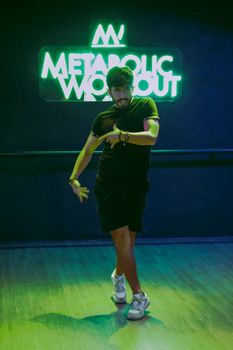 Man dancing energetically under neon lights at a gym in Mexico City.