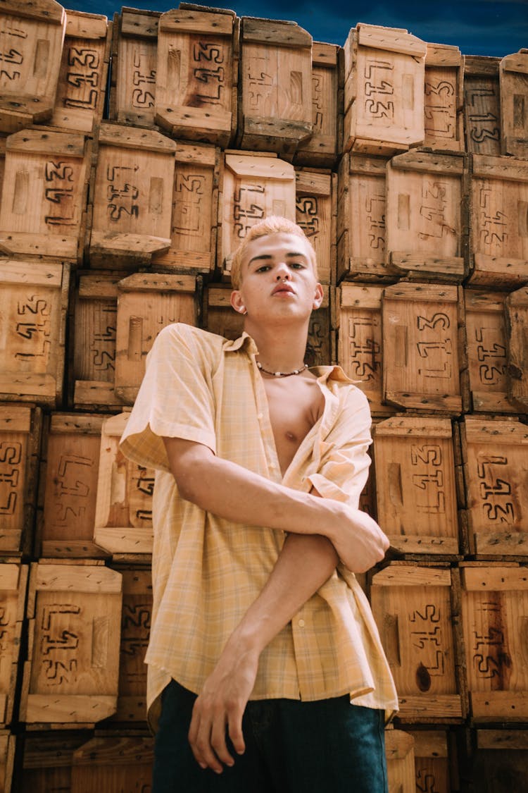 Young Man Posing On The Background Of Wooden Boxes Stack 