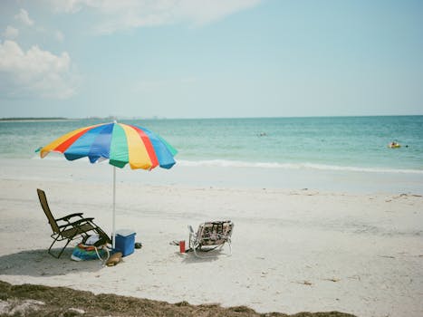 A vibrant beach scene in Clearwater, FL featuring a colorful umbrella and lounge chairs.