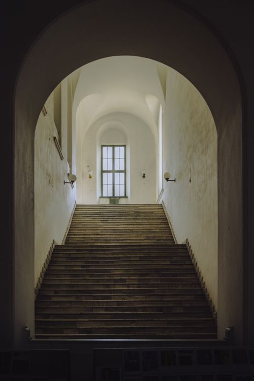 Free Interior view of a grand staircase with an arched entrance and ambient lighting. Stock Photo
