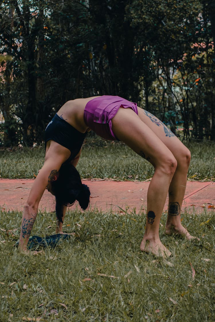 A Woman Bending Her Body On Green Grass Field