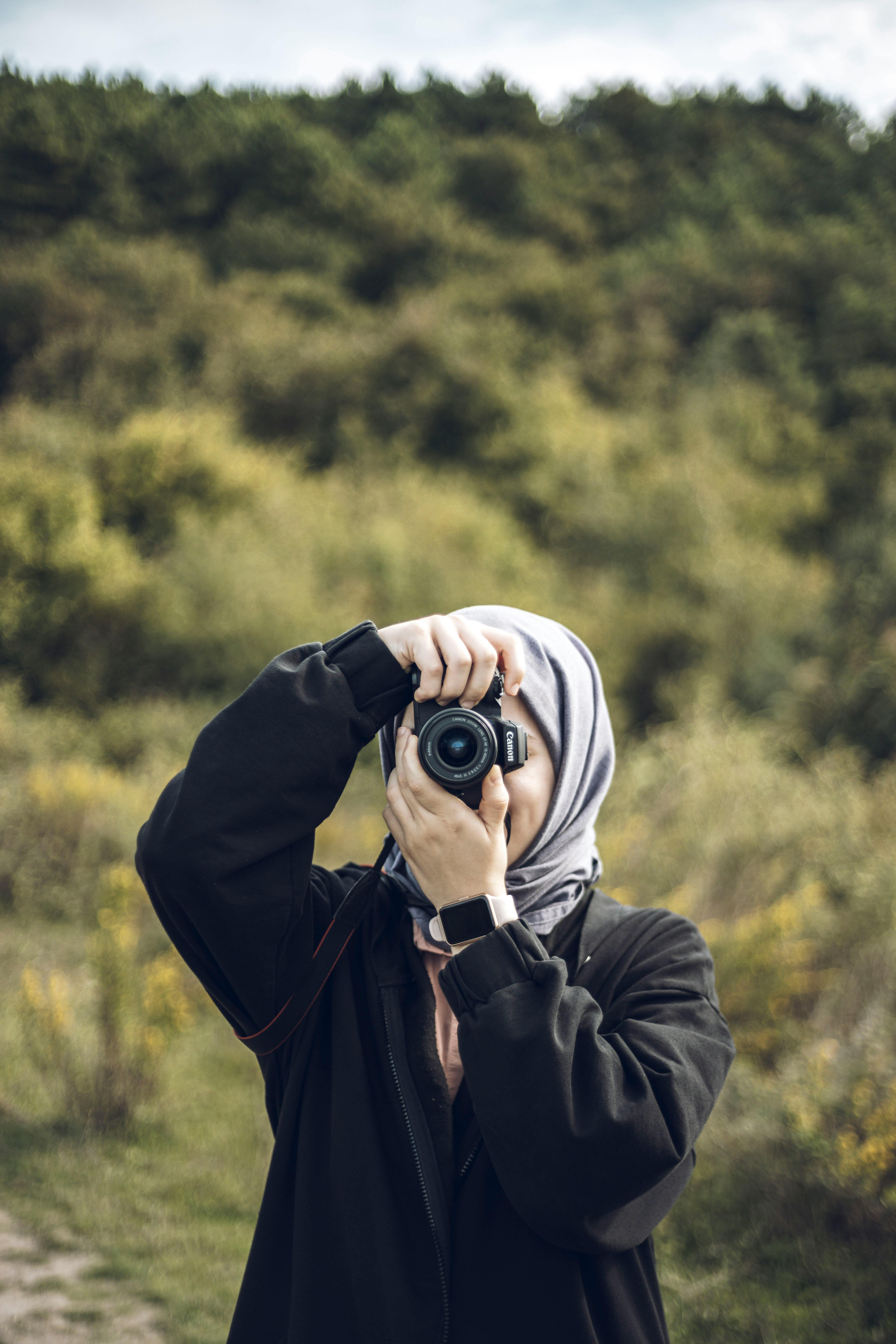 Cute hijab girl with camera and peace sign female photographer