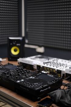 Close-up of DJ equipment on a table in a soundproof music studio setting.