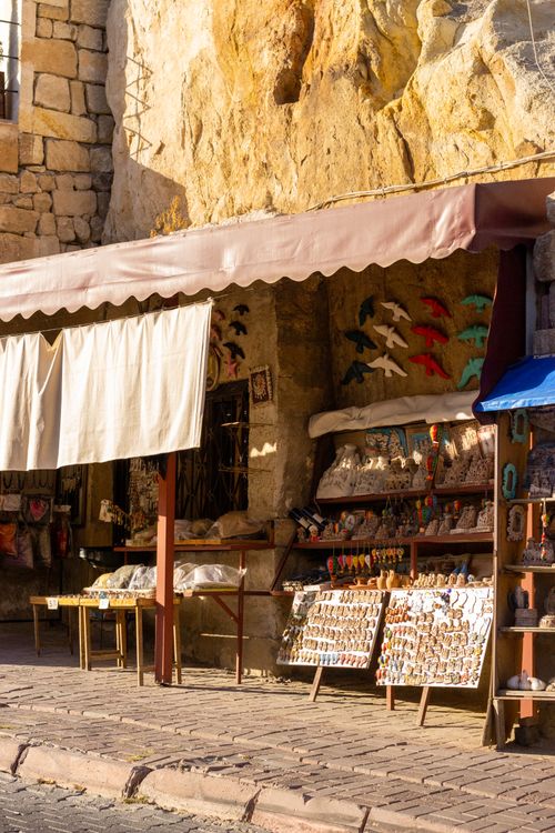 Free A warm-toned photo of a street souvenir shop nestled against a rustic stone wall. Stock Photo