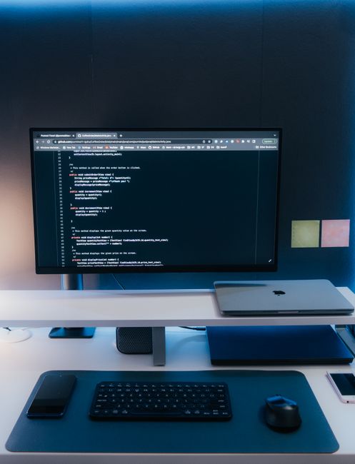 Minimalist home office desk setup with coding on a large monitor, laptop, and gadgets. - Step-by-Step Guide: Setting Up a WordPress Blog on a Tight Budget