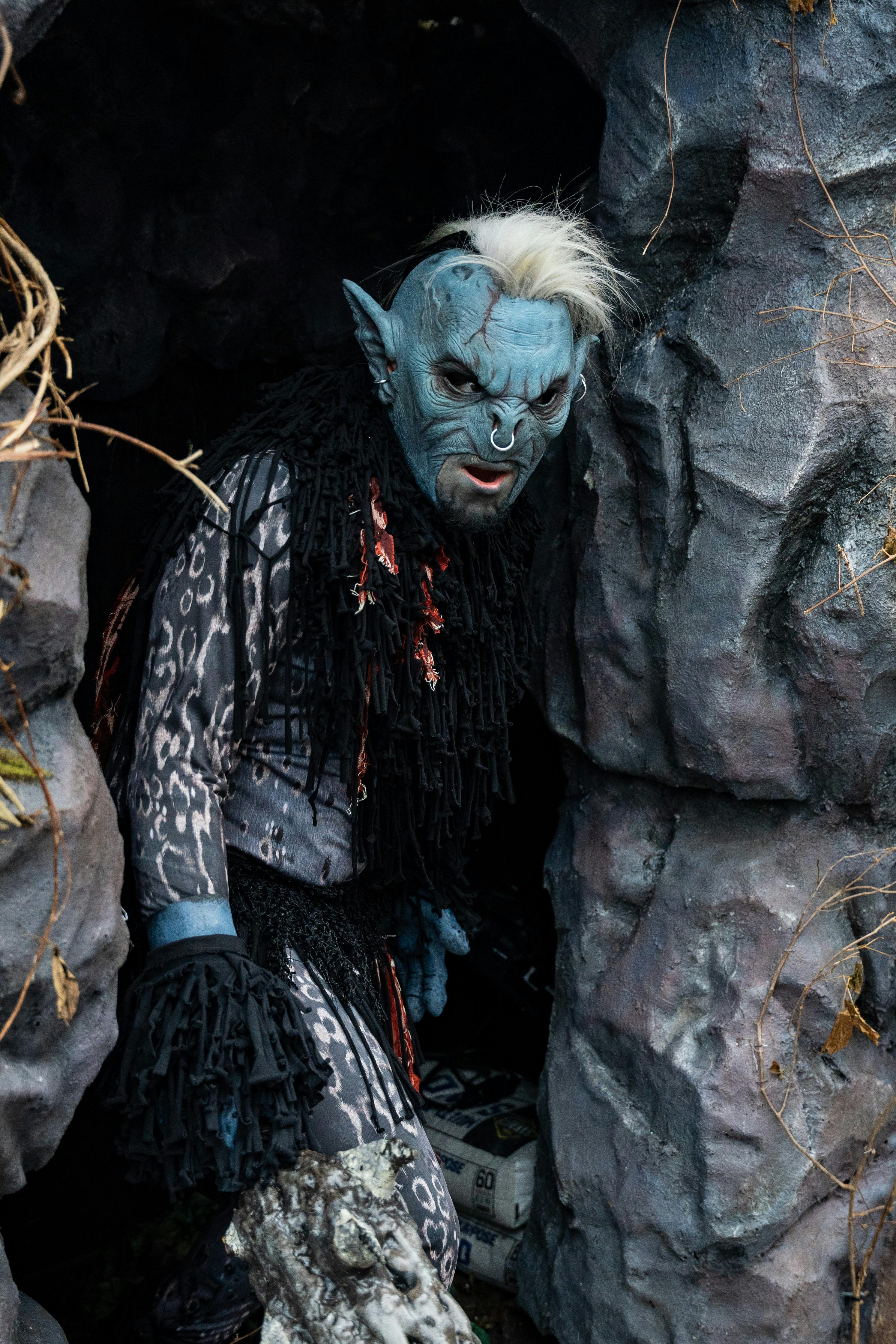 Blue fantasy creature with eerie makeup in a cave, perfect for Halloween concepts.