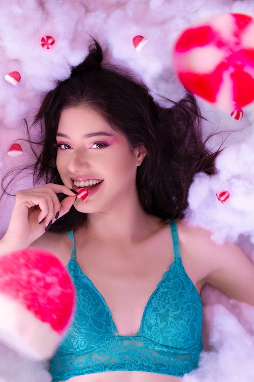 Woman in Teal Brassiere Holding White and Red Candy