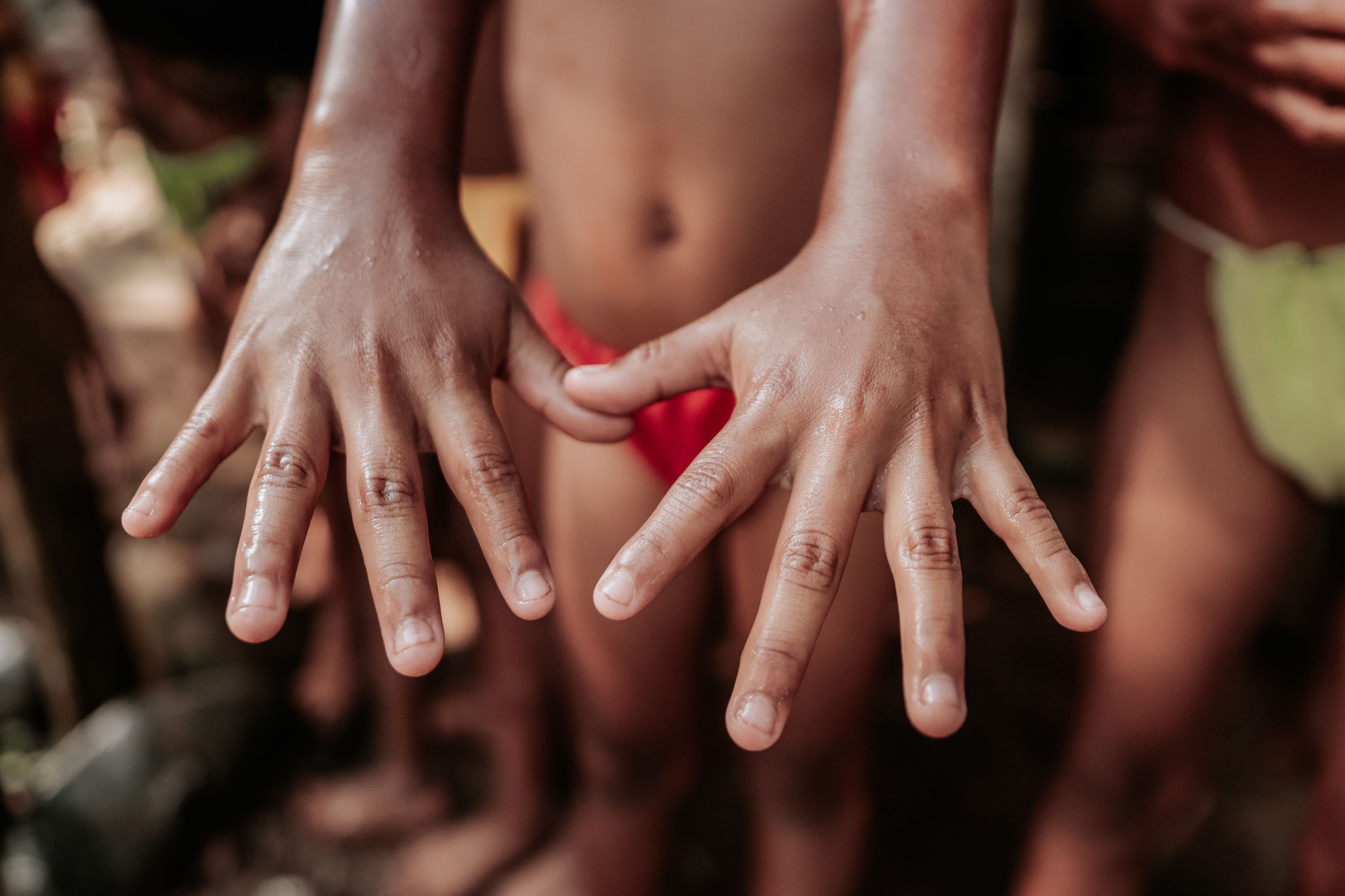 Close-up photo of children's hands outdoors, capturing playful summertime moments.