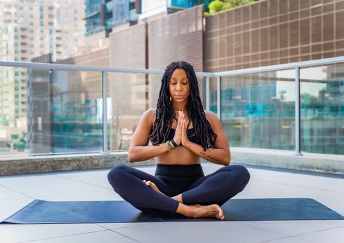 Free A woman practicing yoga and meditation on a rooftop with Dubai's skyline in the background. Stock Photo