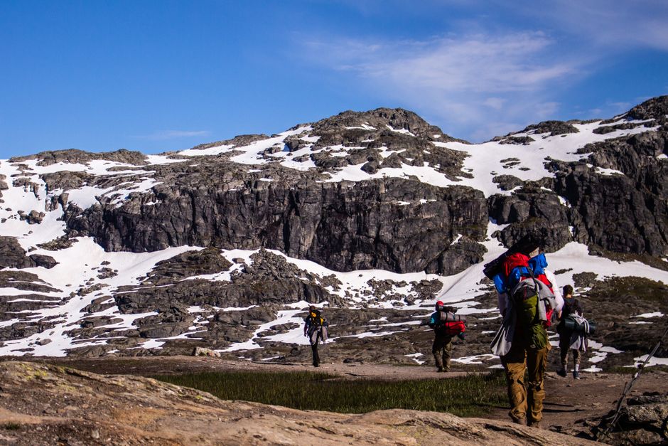 Breathtaking Minibus Northern Lights Chase with Photography from Tromsø Review 2026 - Group of hikers trekking through rocky snow-covered mountains under a clear blue sky.