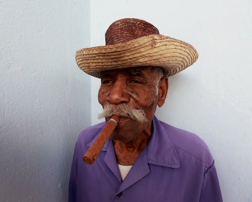 Man in Purple Shirt Smoking a Cigar