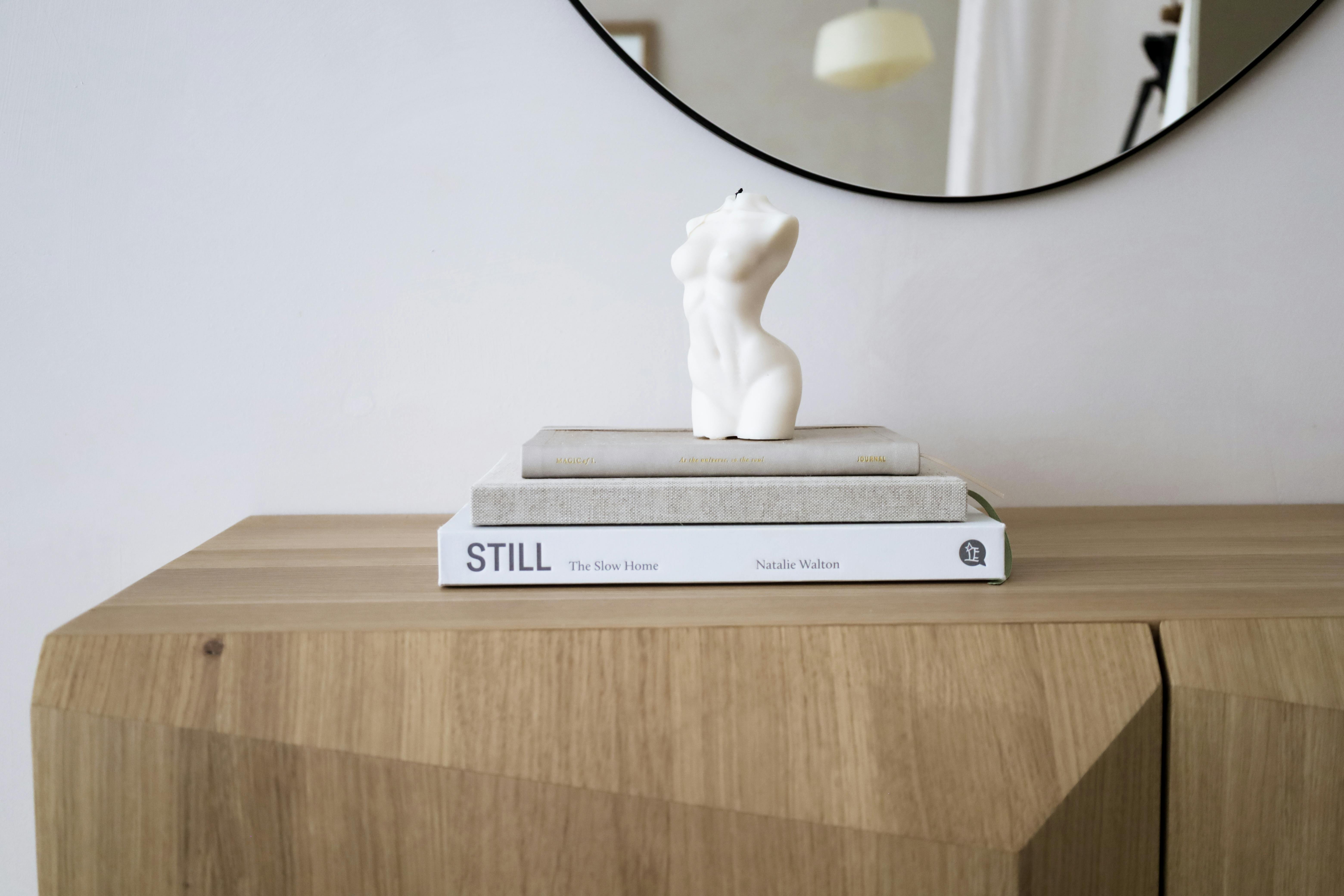 Elegant dresser with a female torso sculpture and books, reflecting minimalist decor.