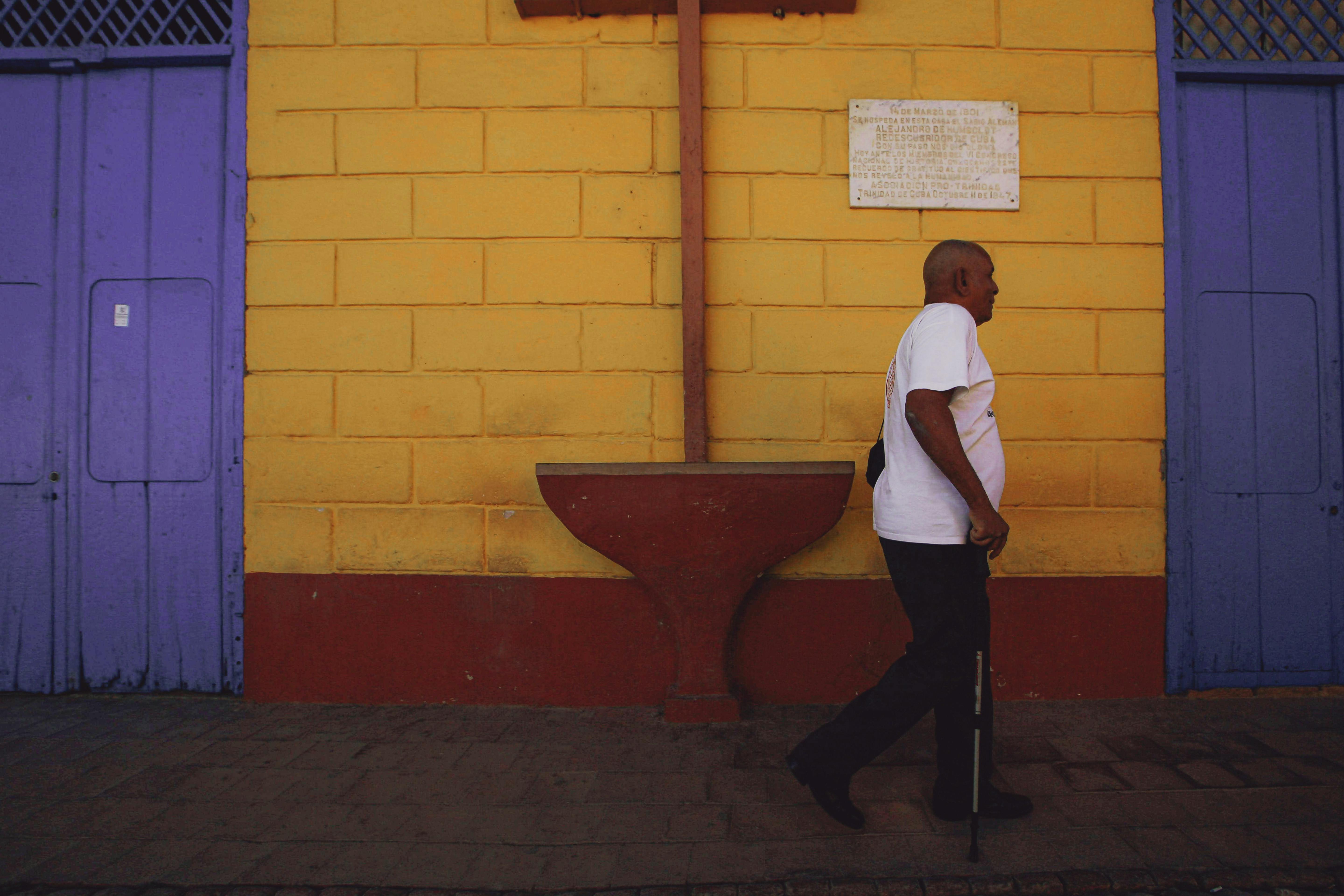 A Man Using Walking Stick while Walking on the Street Side · Free Stock