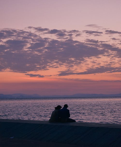 Couple Sitting on the Beach at Sunset 