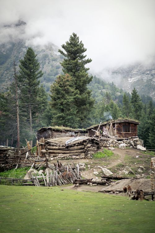 Free Foggy mountain landscape with rustic huts and green forest in Gilgit. Stock Photo