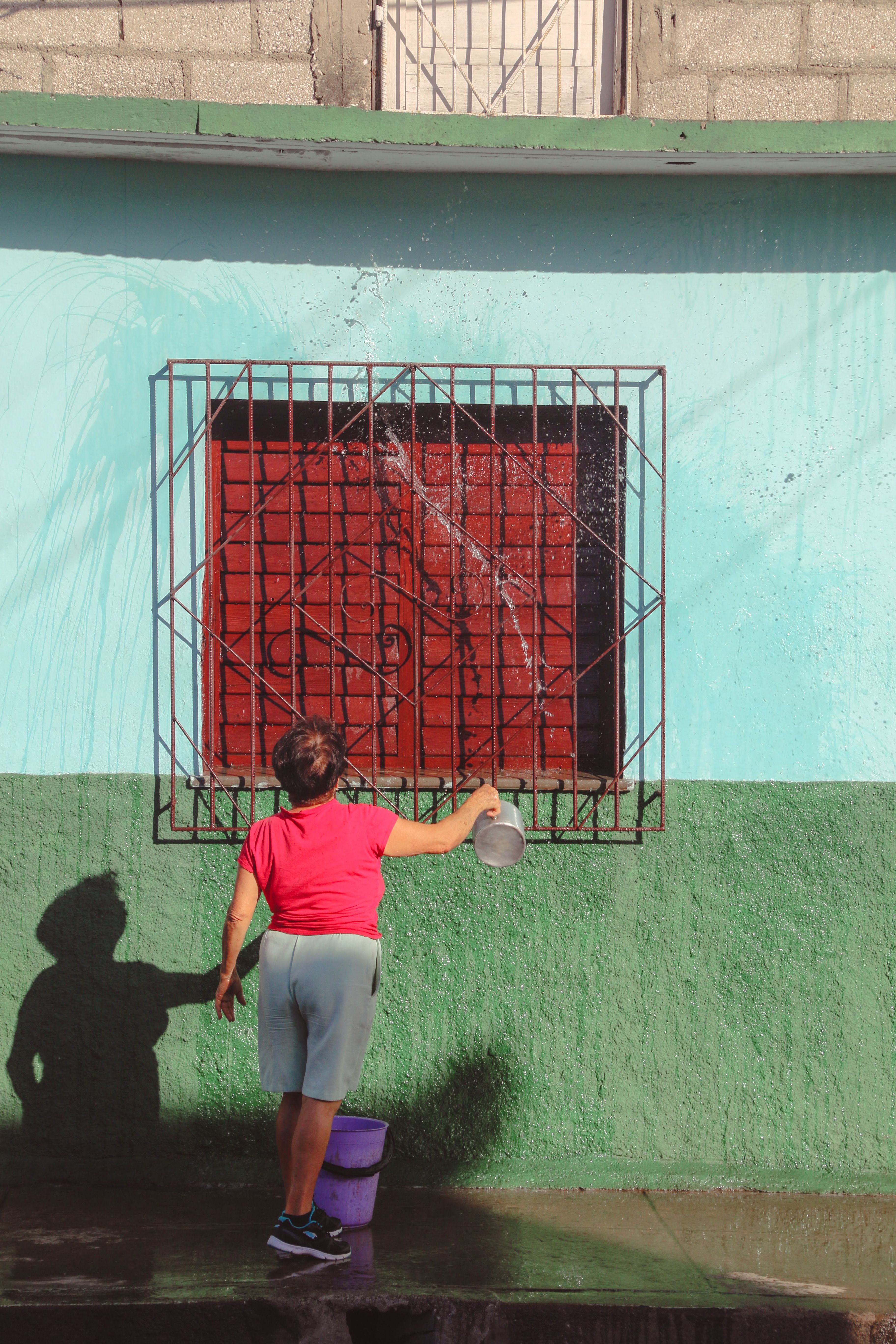 A Person Washing the Wooden Window of a House · Free Stock Photo