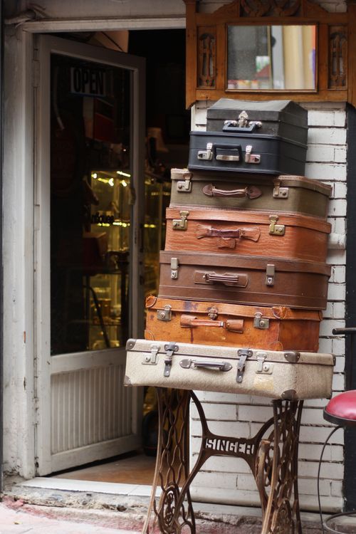Free A collection of vintage suitcases stacked creatively outside an antique store entrance. Stock Photo