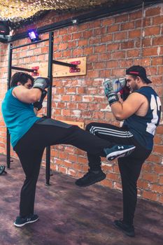 Two men in a gym practicing kickboxing, showcasing athleticism and strength.