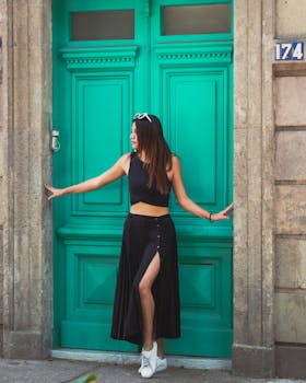 Young woman in stylish attire poses by a vibrant green door, emanating modern fashion vibes.